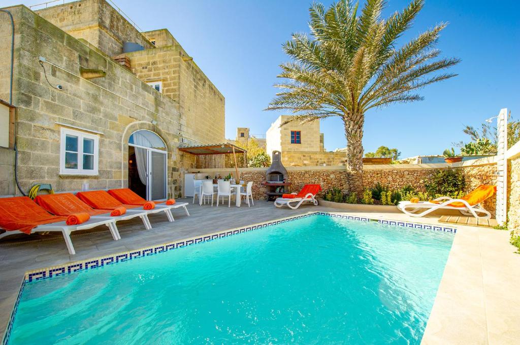 a villa with a swimming pool in front of a house at Dar It-Torri Holiday Home in Kerċem