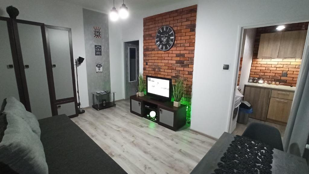 sala de estar con TV y pared de ladrillo en Apartament w Sandomierzu przy Starówce, en Sandomierz