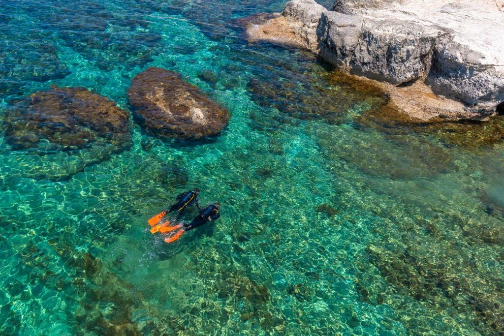 a person in a kayak in the water next to rocks at Cap St Georges Villas in Peyia