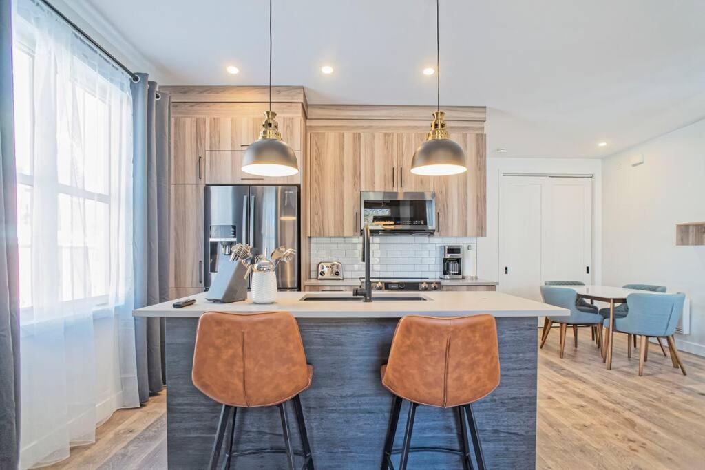 a kitchen with a large island with two bar stools at 201 Condo au rez de chaussée , au coeur de Bromont in Bromont