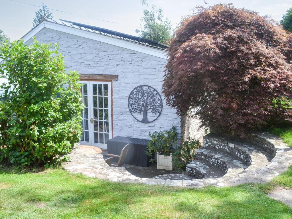 une petite maison avec un banc devant elle dans l'établissement Ty Sally Jones, à Bwlch