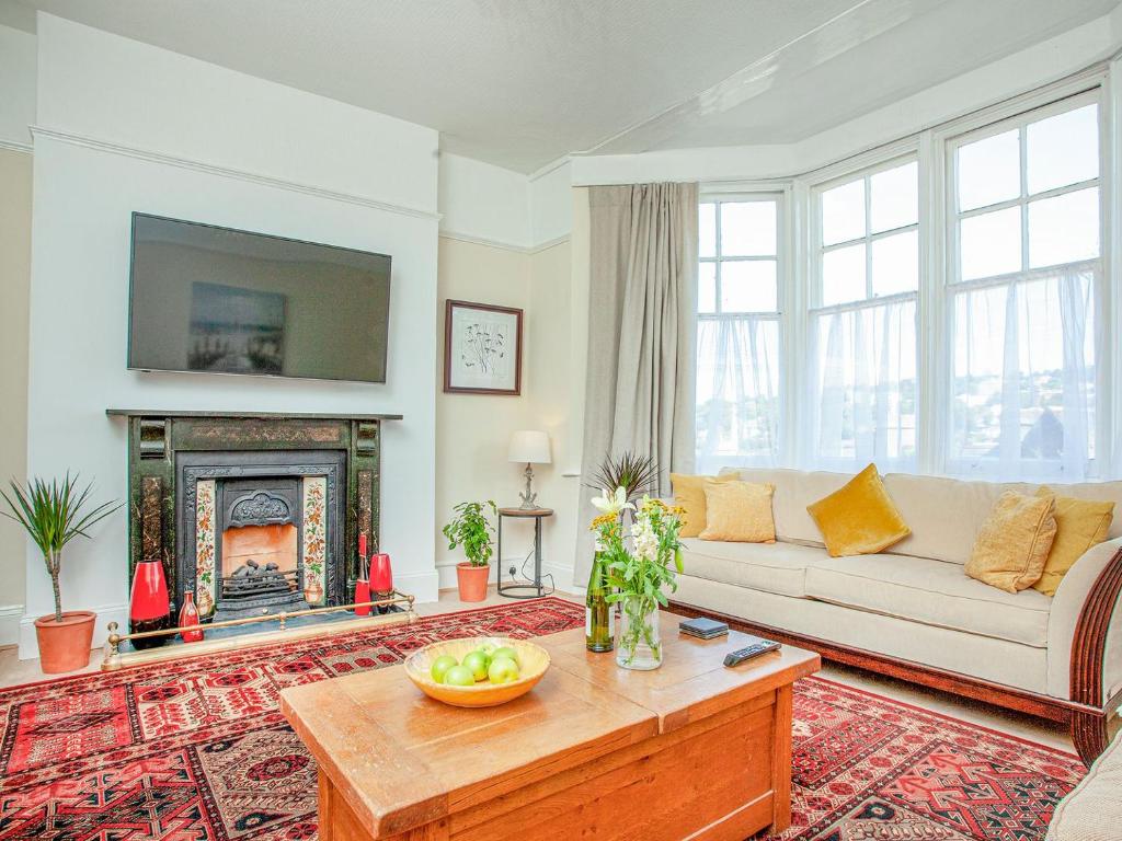 a living room with a white couch and a fireplace at The Coach House At Vane Hill in Torquay