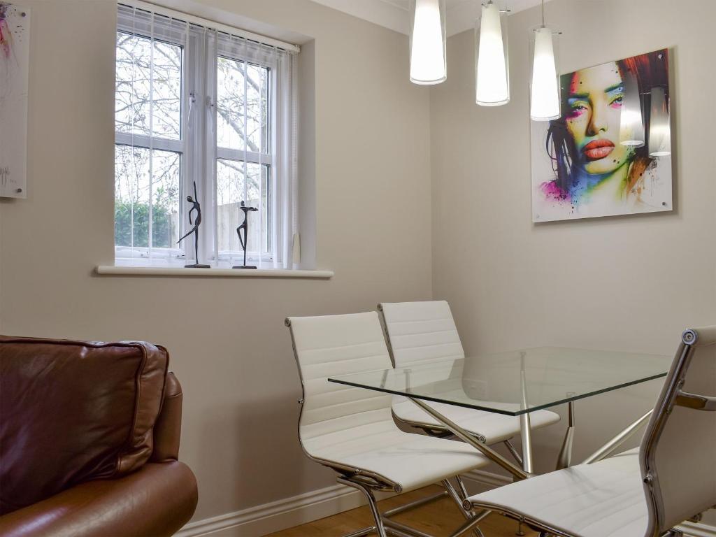 a dining room with a glass table and white chairs at Hollies Cottage 3 - Ukc4522 in Martock