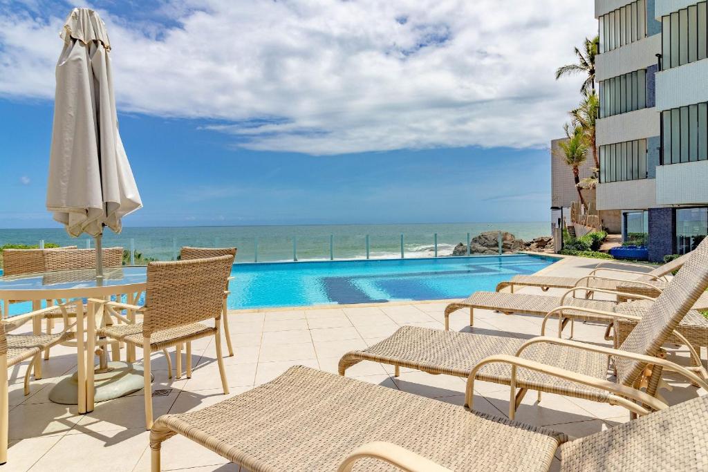un patio con sillas, una sombrilla y una piscina en RV05 Excelente Quarto e Sala, Pé na Areia - Rio Vermelho, en Salvador
