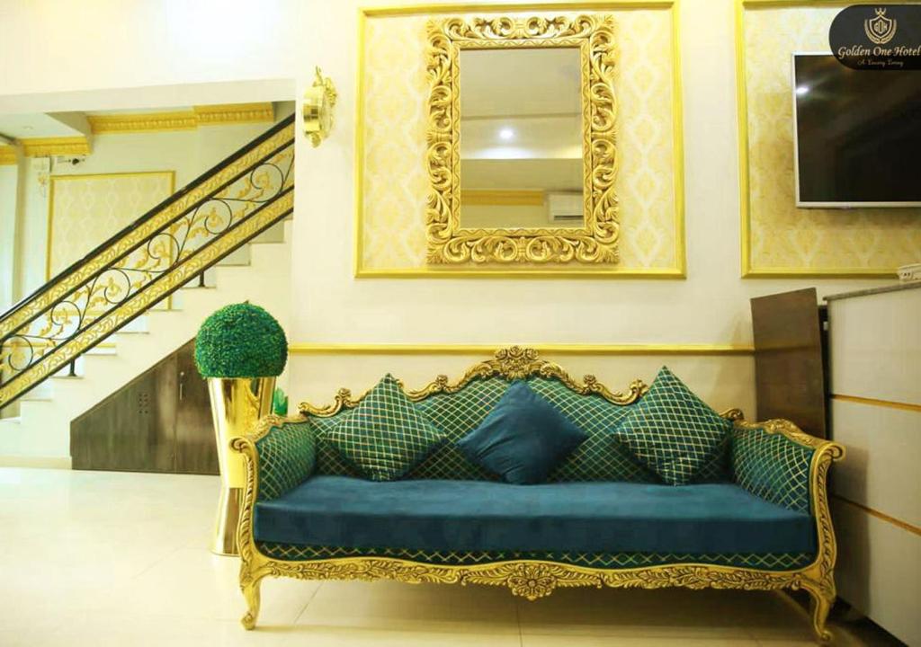 a blue couch in a room with a mirror at Golden One Hotel in Lahore
