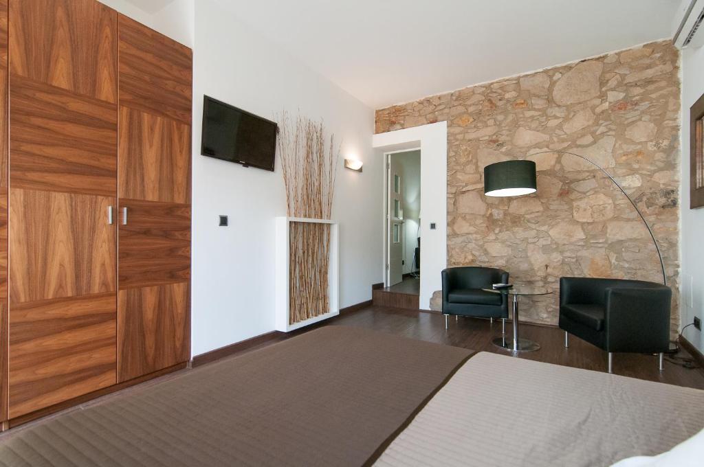 a bedroom with a bed and two chairs and a tv at Alos Apartments Paseo de Gracia-Diagonal in Barcelona