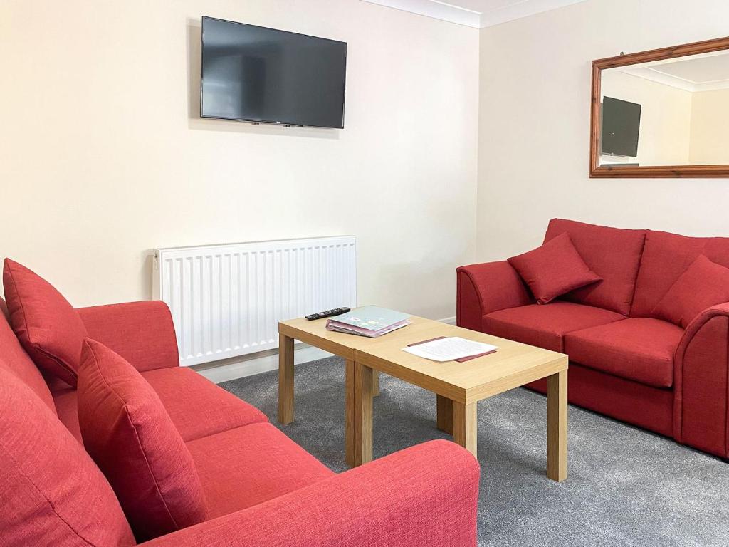 a living room with two red couches and a table at Uk40237 - Beach Bank Bungalow in Lympne