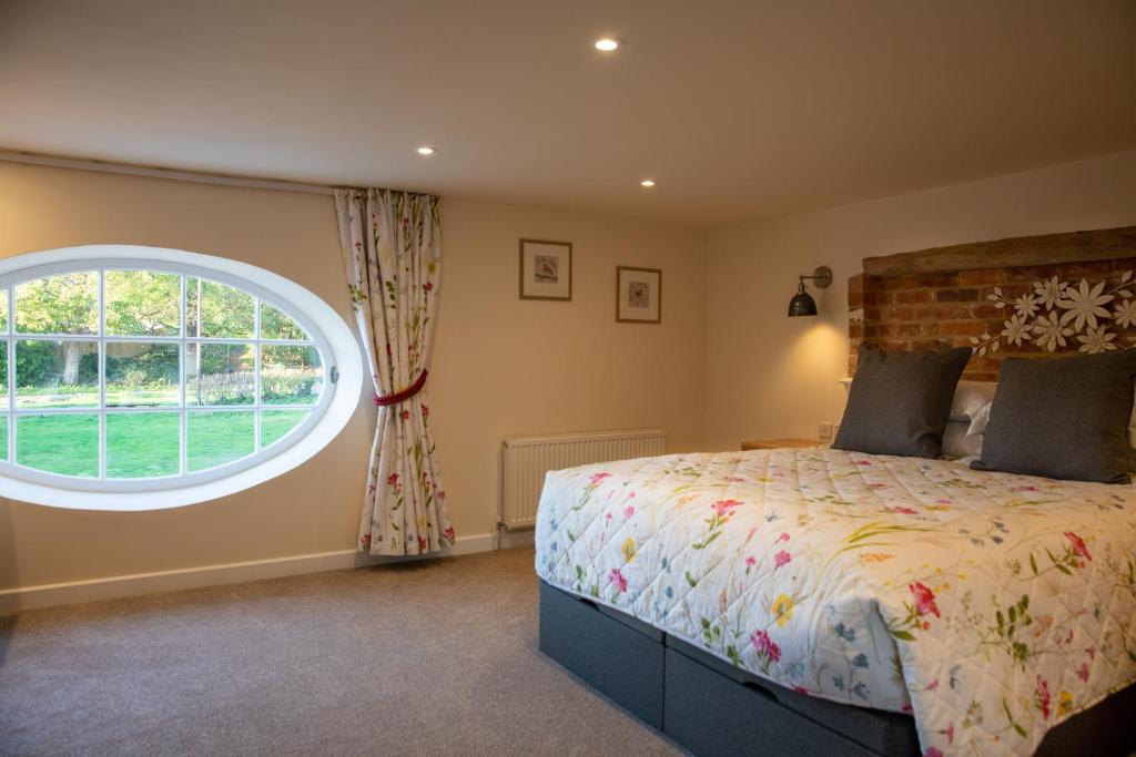 a bedroom with a bed and a large window at Rollestone Coach House in Shrewton