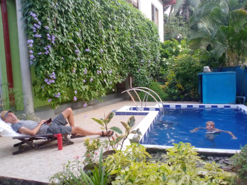 two people laying on chairs next to a swimming pool at Abha Villa with Private pool in Galle