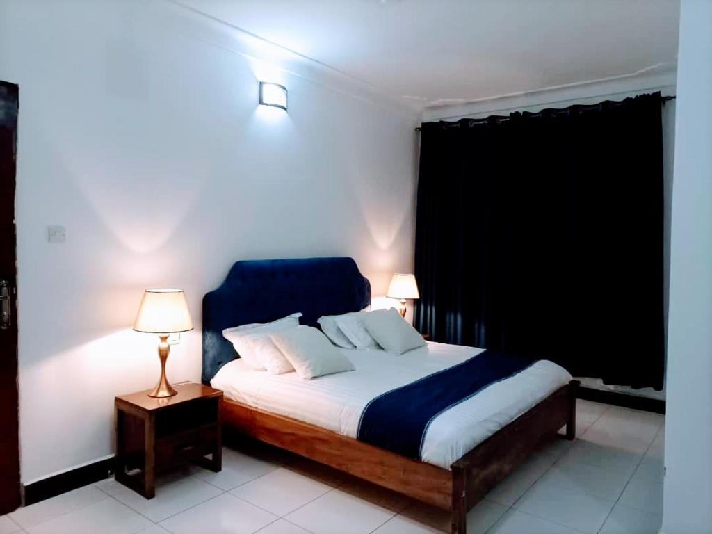 a bedroom with a bed and two lamps on tables at Villa Bunyonyi in Kabale