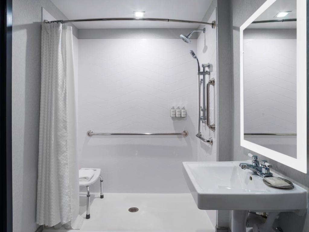 a white bathroom with a sink and a shower at voco - The Cadence, an IHG Hotel in Niagara Falls
