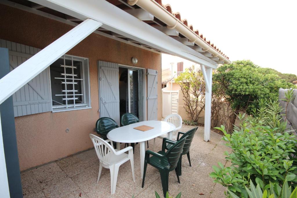 d'une terrasse avec une table et des chaises blanches. dans l'établissement Maison de vacances, 4 -6 couchages, 200m de la mer, Residence securisee LES SENTOLINES, PORTIRAGNES PLAGE LRSEN47, à Portiragnes
