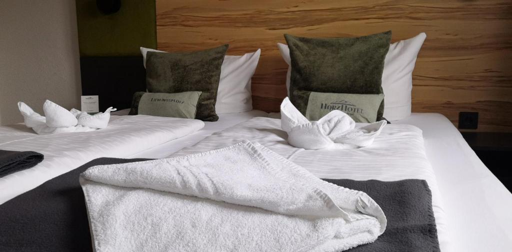 2 camas con toallas blancas y almohadas en HarzHotel Güntersberge, en Güntersberge