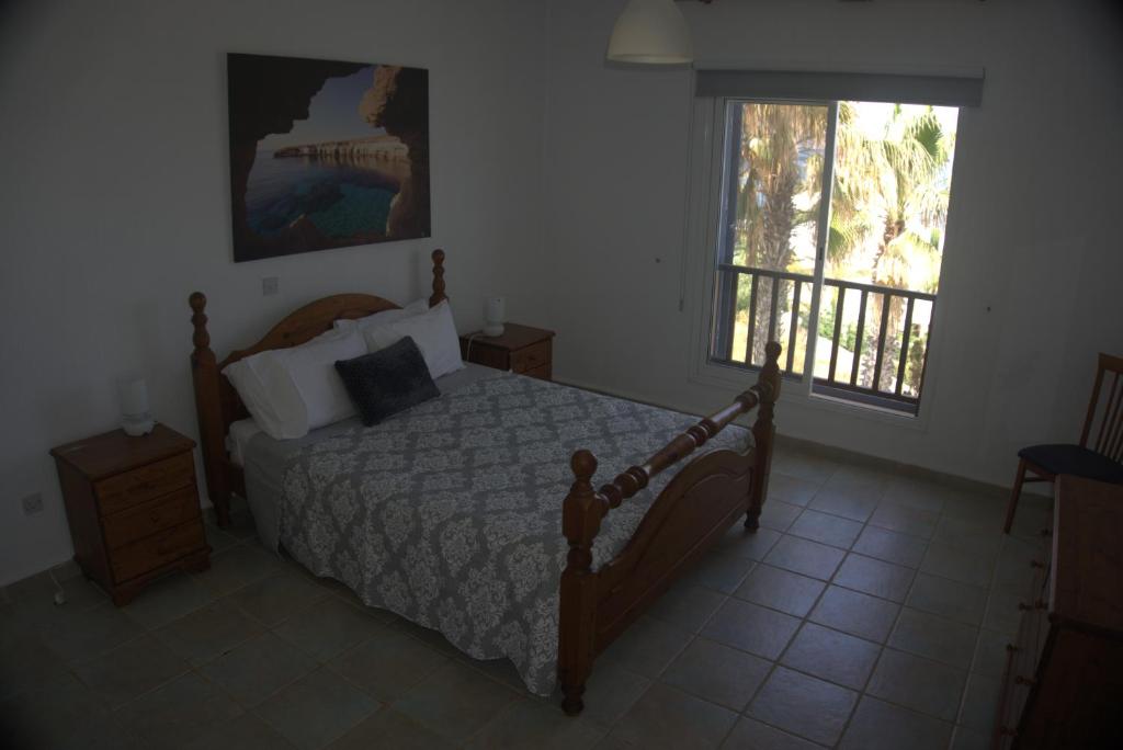 een slaapkamer met een bed en een raam met een balkon bij Sky Villa in Paphos City