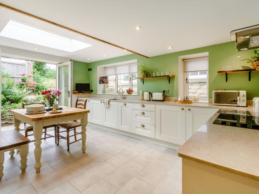 a kitchen with green walls and white cabinets and a table at 1 Chapel Terrace in Ebberston
