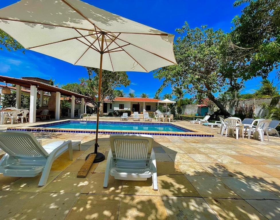 - une terrasse avec des chaises et un parasol à côté de la piscine dans l'établissement Casa Ana Frank, à Parajuru