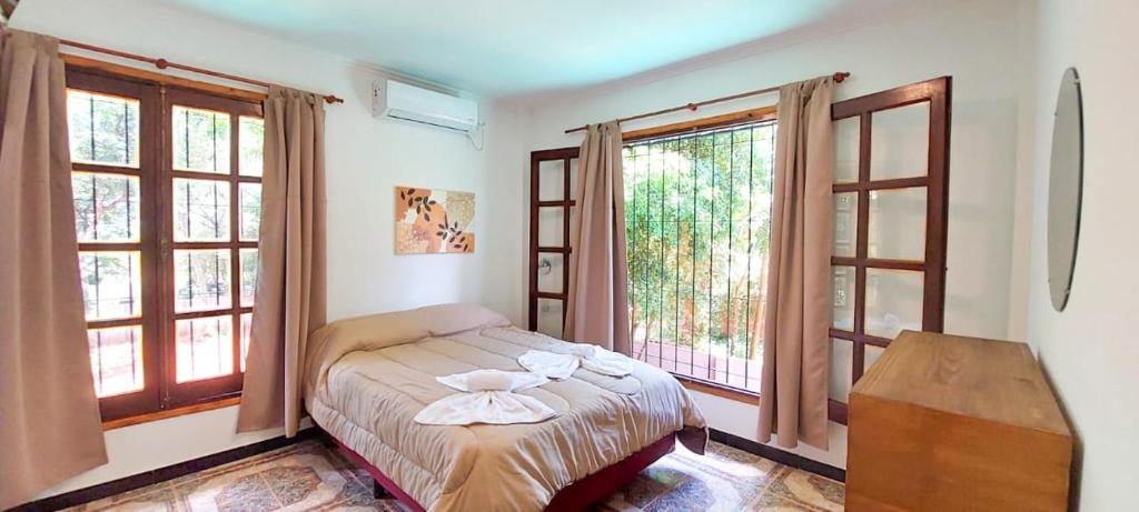 伊瓜蘇港的住宿－Orquídeas De La Selva，一间卧室设有一张床和两个窗户。