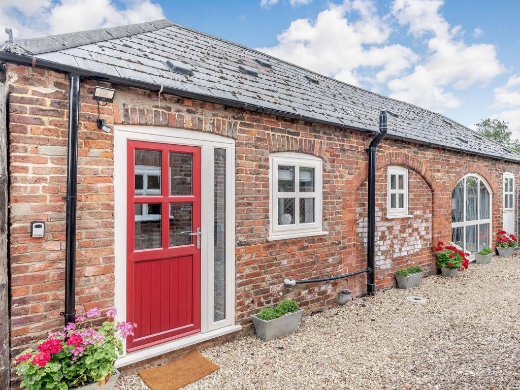 een bakstenen huis met een rode deur en ramen bij The Annexe hornsland Barn in Wyberton