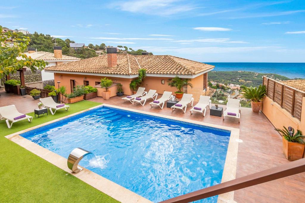 a swimming pool with chairs and a house at Villa Origami in Lloret de Mar