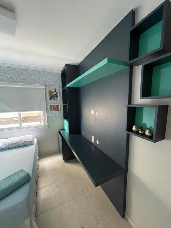 um quarto com uma cama e uma secretária com prateleiras verdes em Apartamento Confortável e Completo - JTR em Maceió