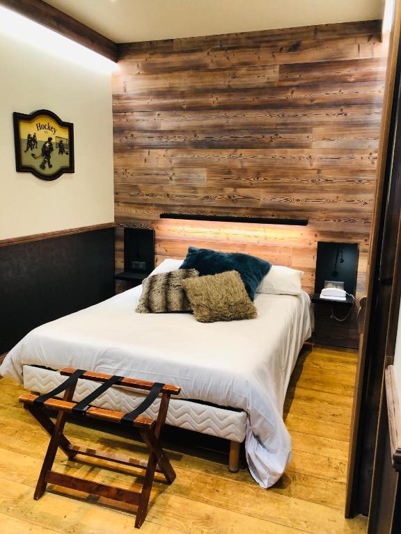 a bedroom with a bed with a wooden wall at Logis Hotel Des Bains in Gérardmer