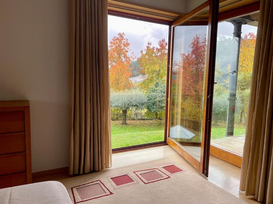 a bedroom with a large window with a view at Quinta Picouto de Cima in Guimarães