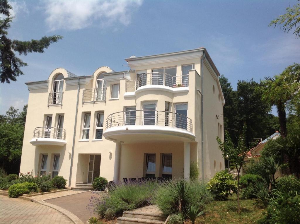 a large white house with balconies and trees at Apartments Villa Majda in Matulji