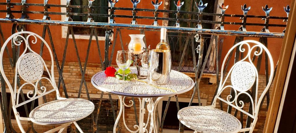 a table with two chairs and a bottle and glasses at My Rialto Palace in Venice
