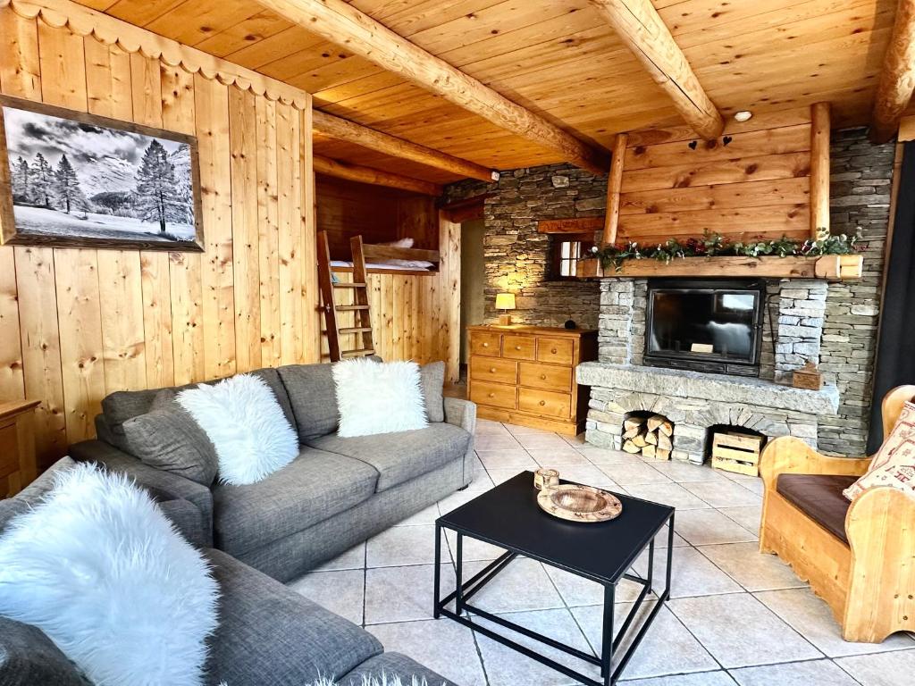 ein Wohnzimmer mit einem Sofa und einem Kamin in der Unterkunft Chalet Les Cocales Résidence Séjour et Nuitées B&B - Appartement Pin Sylvestre in Bessans