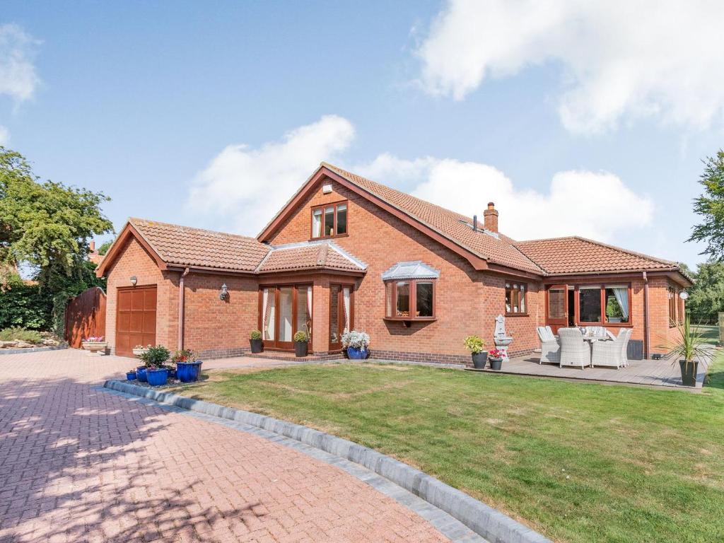 a brick house with a patio and a yard at The Hawthorns in Ottringham