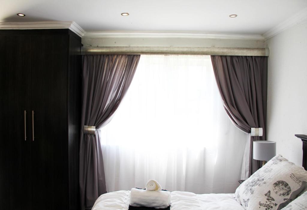 a bedroom with a bed and a large window at La Coscello Guest House in Edenvale