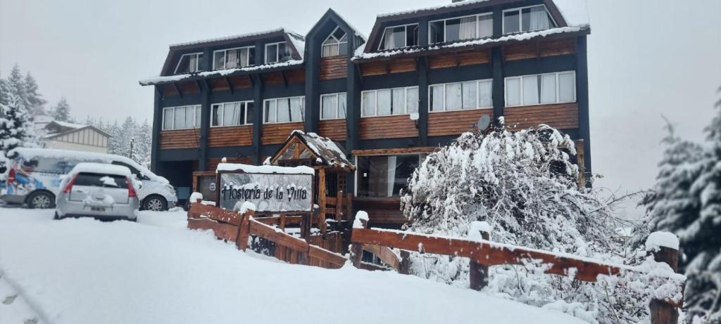 a snow covered house with a car parked in front of it at Hosteria de la Villa - Moonski in San Carlos de Bariloche