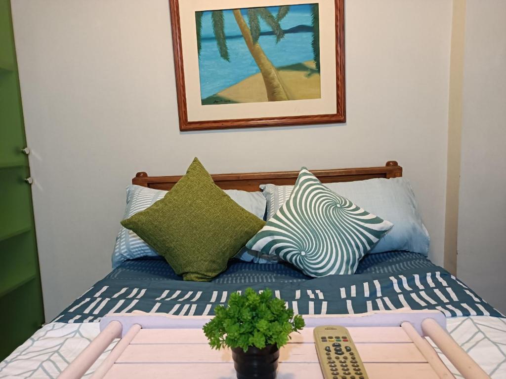 uma cama com almofadas e uma mesa com uma planta em WestParc Cedar Alabang em Manilla