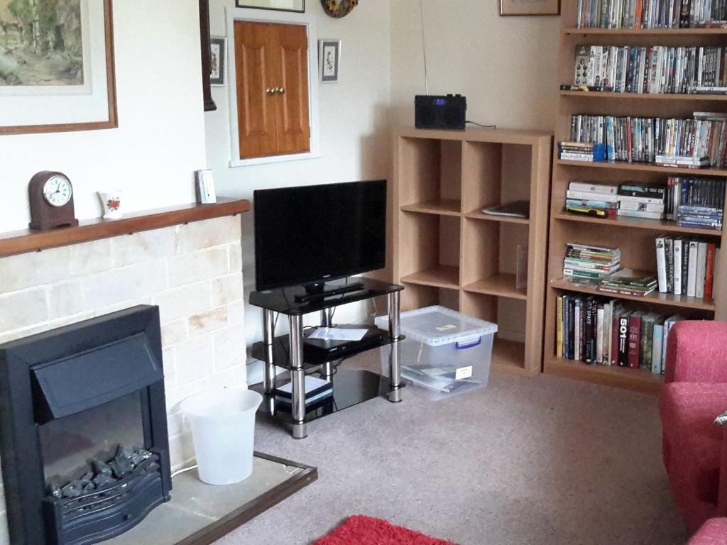 a living room with a television and a fireplace at Sunshine Cottage in Fairford