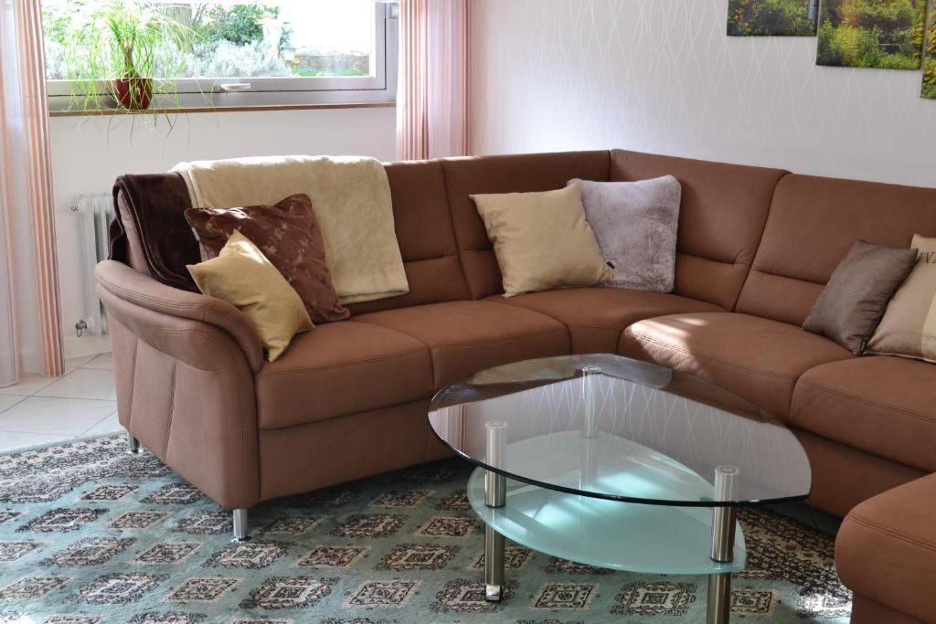 a living room with a brown couch and a glass table at Ferienwohnung Zauber der Pfalz nahe Speyer in Römerberg