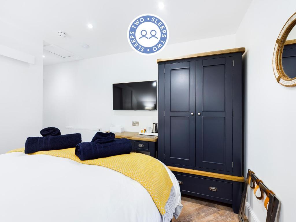 a bedroom with a bed and a black cabinet at Driftwood Boutique Guest House in Rhosneigr