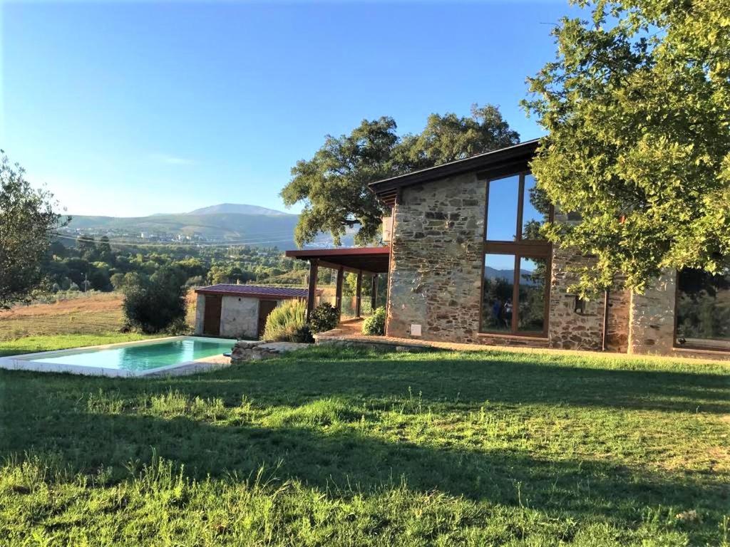 een stenen huis met een zwembad in de tuin bij Quinta Lourena - Casa do Desassossego in Covilhã