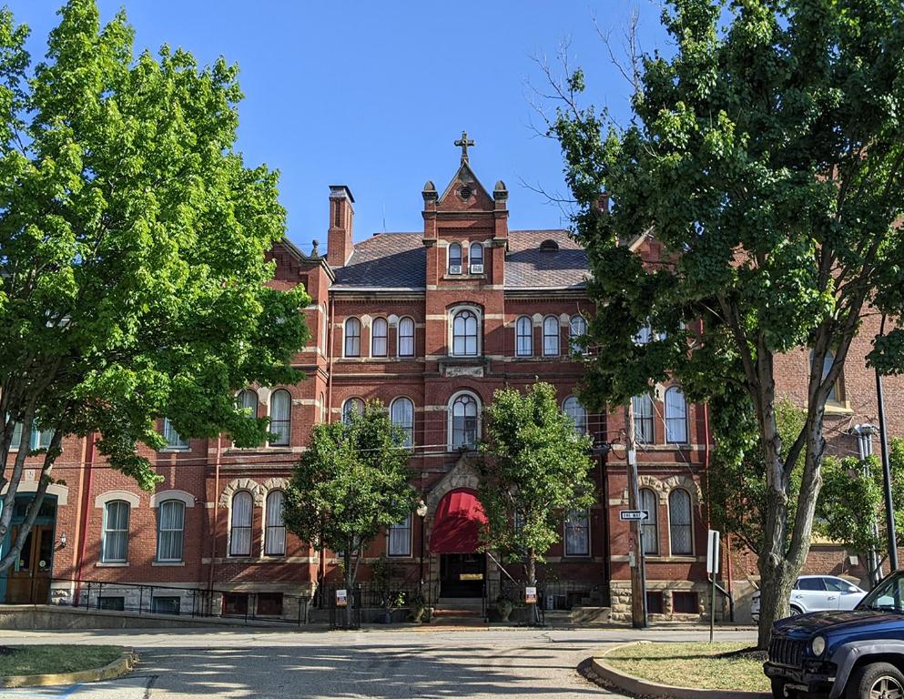 a large red brick building with trees in front of it at The Priory Hotel in Pittsburgh