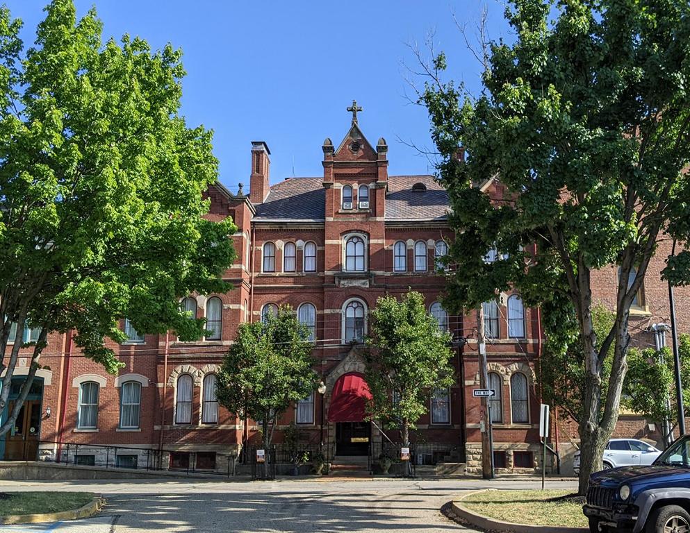 een groot gebouw van rode baksteen met bomen ervoor bij The Priory Hotel in Pittsburgh