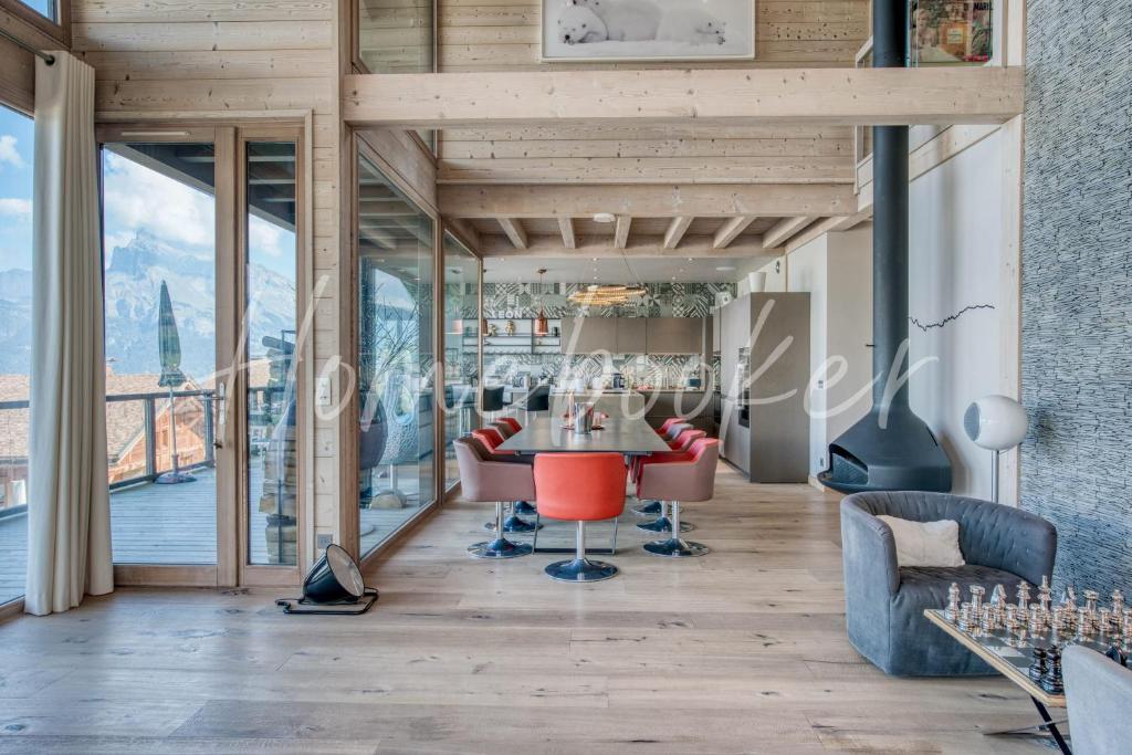 un salon avec une table, des chaises et des fenêtres dans l'établissement Chalet Mage, à Combloux