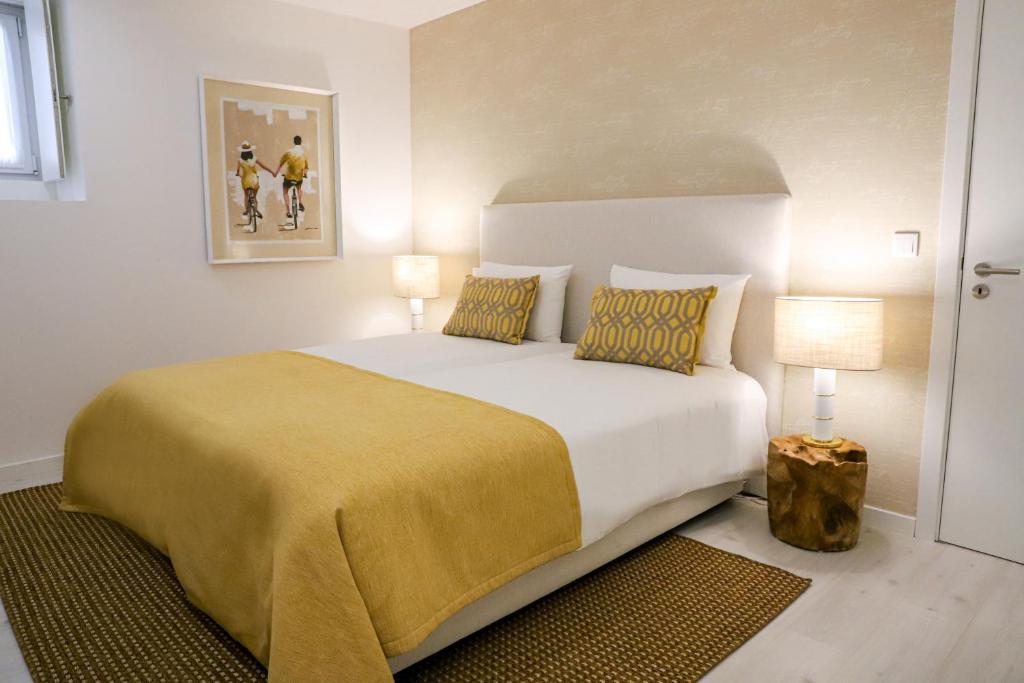 a bedroom with a large bed with a yellow blanket at Canto dos Poetas in Leiria