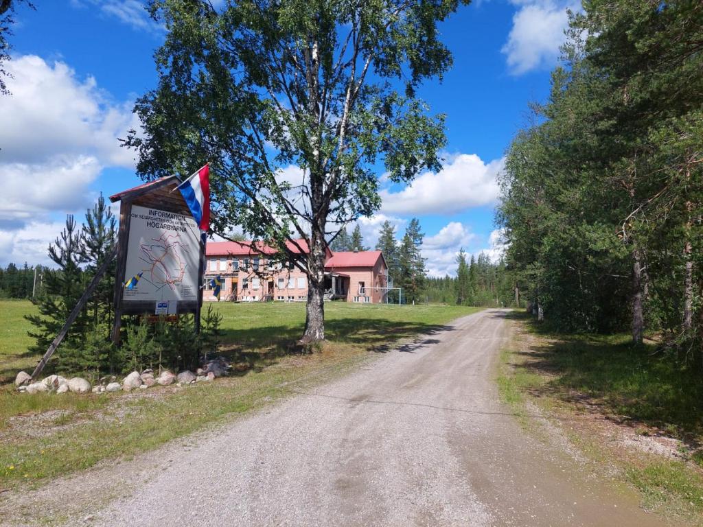 a dirt road with a flag and a house in the background at Hotell Nederhögen Vildmarkscenter in Rätan