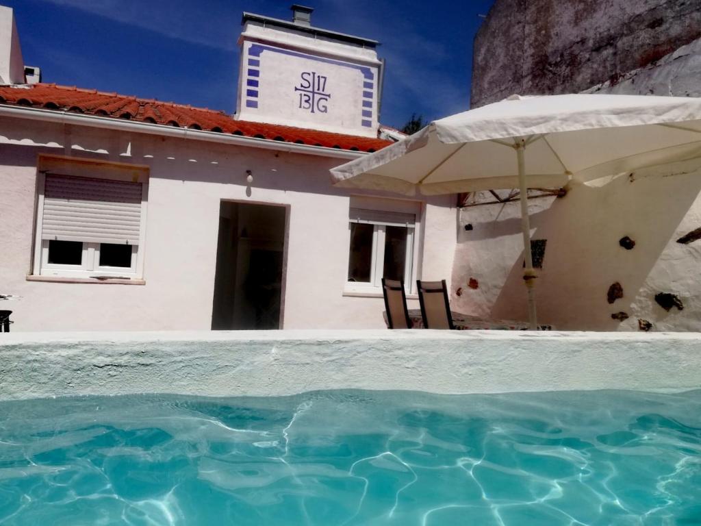 a house with an umbrella and a swimming pool at Casa do Corticeiro in Arraiolos