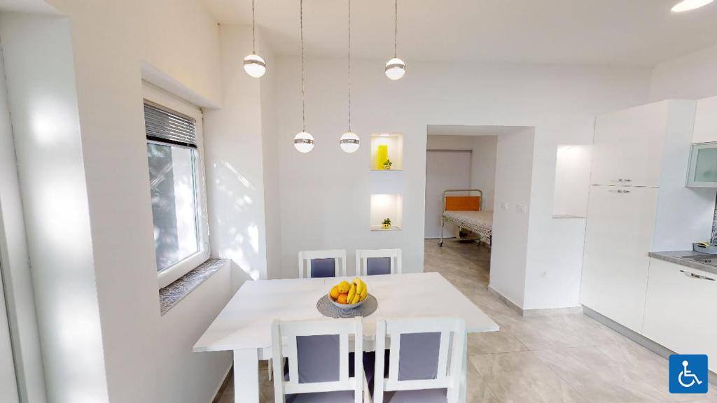 a white kitchen with a table with bananas on it at Apartments Mare in Pula