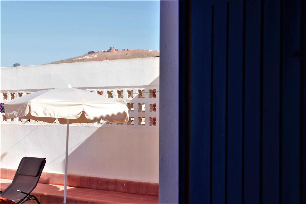a white umbrella and a chair on a balcony at Asunfou : Appartement d'apaisement in Mirleft