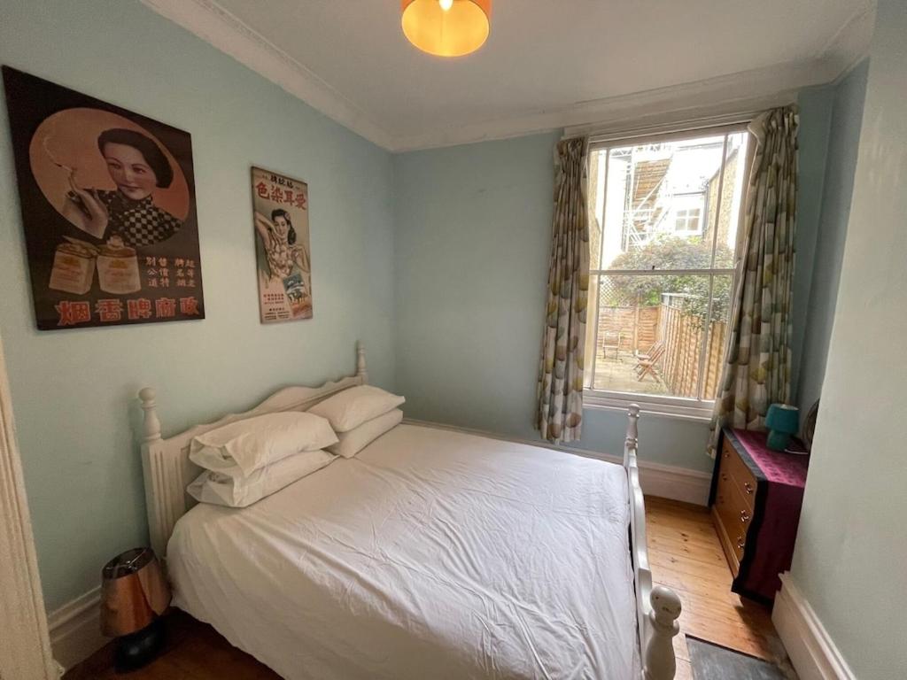 ロンドンにあるBeautiful ground floor garden flatのベッドルーム(白いベッド1台、窓付)