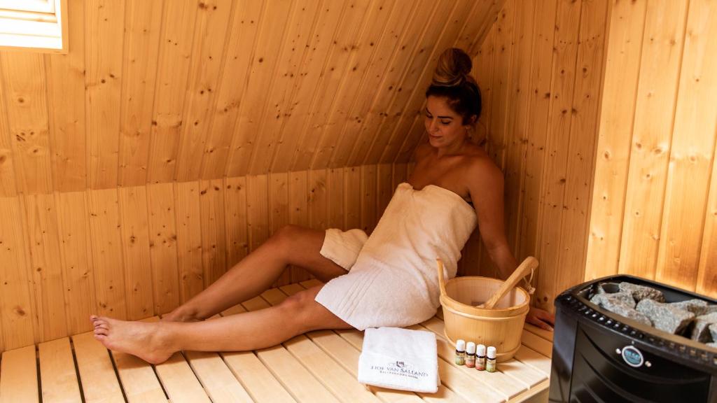 a woman is sitting in a sauna at Hof van Salland Hellendoorn in Hellendoorn