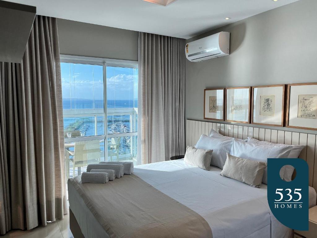 a bedroom with a large bed with a large window at Amplo Quarto e Sala Vista Baía de Todos os Santos in Salvador