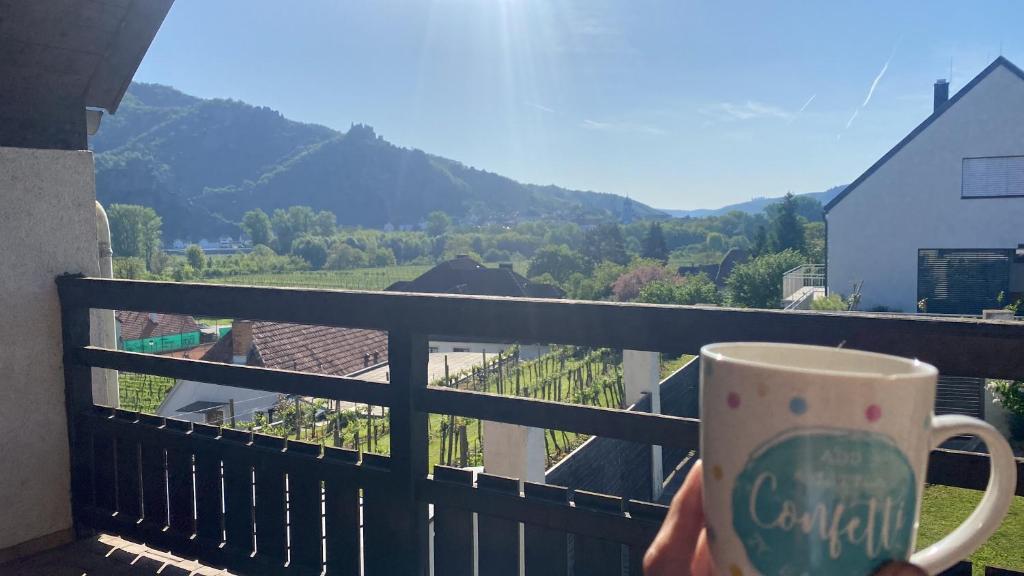 a person holding a cup of coffee on a balcony at Rossatz 69 in Rossatz