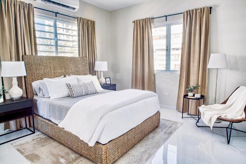 um quarto com uma cama, uma cadeira e janelas em Enjoy our Luxurious Penthouse in Condado! em San Juan